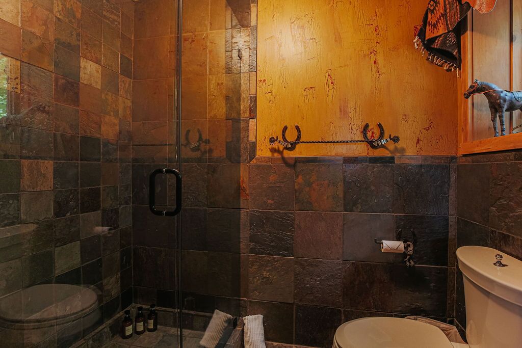 A bathroom with a glass shower enclosure, a toilet, and a sink.