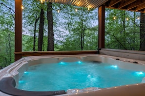 Ein Whirlpool mit einer Holzterrasse und Blick auf einen Wald.