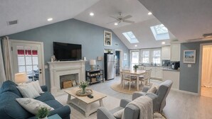 A spacious living room with a fireplace, a television, and a dining area with a table and chairs. - ONE Minute walk to BEACH! High end home special! TOP RATED GUEST FAVORITE (Dennis)