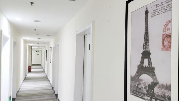 Un pasillo de hotel con un cuadro enmarcado de la Torre Eiffel en la pared.
