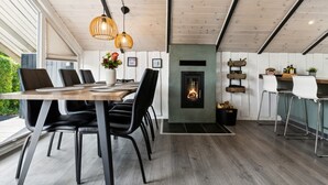 Et moderne spiseområde med et træbord, sorte stole og en pejs.