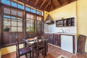 Une cuisine avec des meubles en bois, un réfrigérateur blanc et une fenêtre avec des stores.
