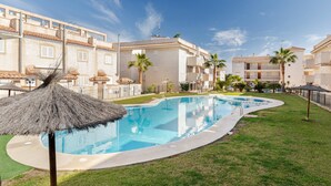 A swimming pool surrounded by grass, palm trees, and buildings with balconies. - Apartment 'Aguilas Con Ac Y Piscina' with Shared Pool, Wi-Fi and Air Conditioning (Águilas)