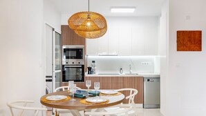 A modern kitchen with white cabinets, a dining table with white chairs, and a hanging light fixture. - Apartment 'Aguilas Con Ac Y Piscina' with Shared Pool, Wi-Fi and Air Conditioning (Águilas)