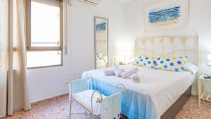 Un dormitorio con cama, una silla, un ventanal, un espejo y obras de arte en la pared.