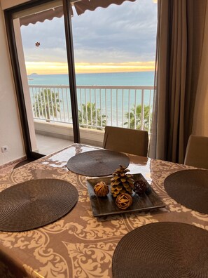A balcony with a view of the sea, a table with woven placemats, and decorative items.