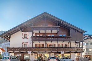A multi-story building with a traditional Alpine architectural style, featuring balconies and a sign for 'IPB CASSA'.