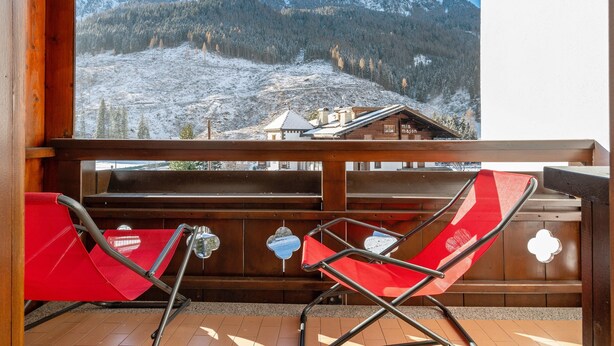 A balcony with red chairs, a wooden railing, and a view of a snowy mountain landscape. - Apartment 'Appartamento 2-3 Persone' with Mountain View, Balcony and Wi-Fi (Canazei)