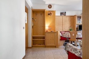 A wooden interior with a kitchen area, a dining table with chairs, and a small seating area.