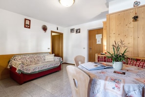 A room with a sofa, a table with a plant, a wooden cabinet, and a door.