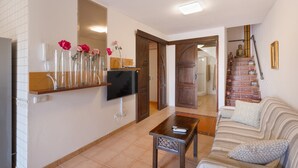 Een woonkamer met een bank, een salontafel, een televisie en een trap naar een andere kamer.