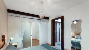 Een slaapkamer met een bed, een nachtkastje, een lamp, een plafondlamp, een schuifdeur en een spiegel aan de muur.