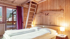 Ein Schlafzimmer in einer Holzhütte mit einem Bett, einer Leiter und einem Nachttisch mit einer Lampe.