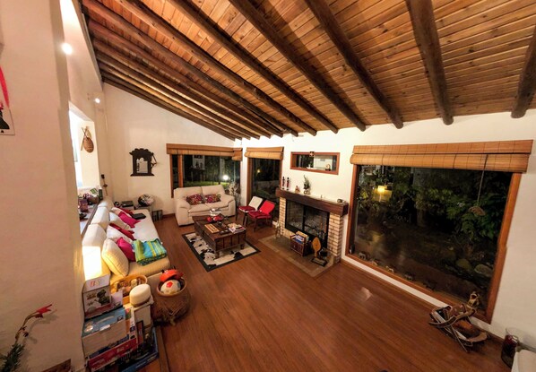 A spacious living room with a wooden ceiling, a fireplace, and large windows. - 3-room beautiful cottage close to Laguna Guatavita (Cundinamarca)