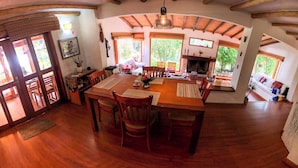 A spacious dining area with a wooden table and chairs, large windows, and a fireplace. - 3-room beautiful cottage close to Laguna Guatavita (Cundinamarca)