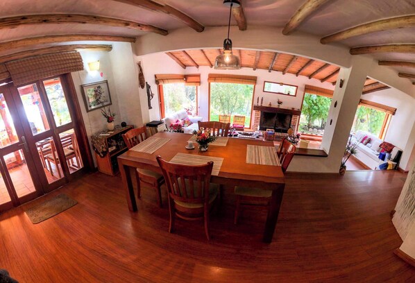 Un'ampia sala da pranzo con tavolo e sedie in legno, ampie finestre e un caminetto.