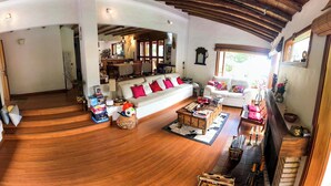 A spacious living area with a wooden ceiling, a sofa with red cushions, a coffee table, and a fireplace. - 3-room beautiful cottage close to Laguna Guatavita (Cundinamarca)