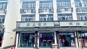 Un edificio tradicional de varios pisos, con amplios ventanales y techo de tejas.