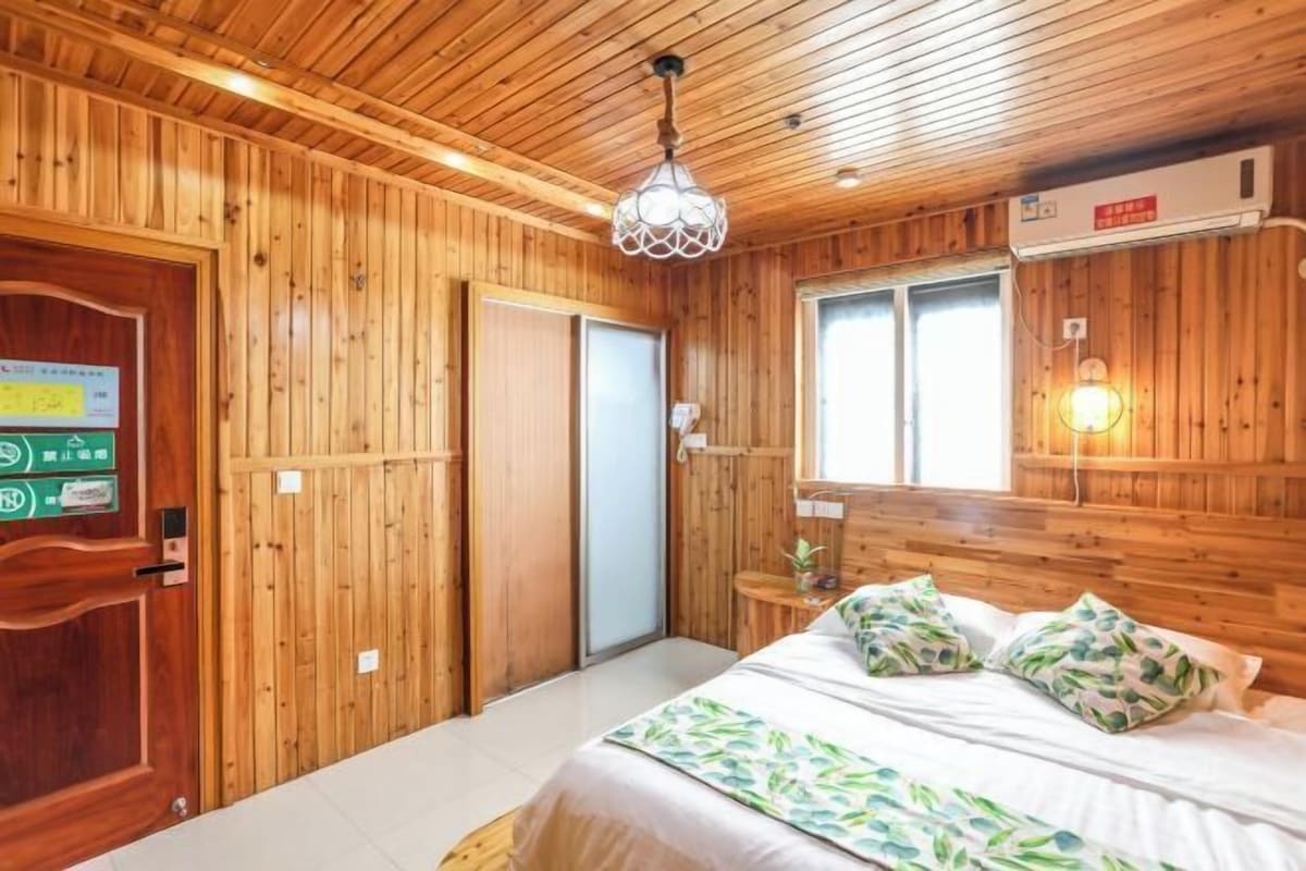 A wooden-paneled room with a bed, a door, and a window.