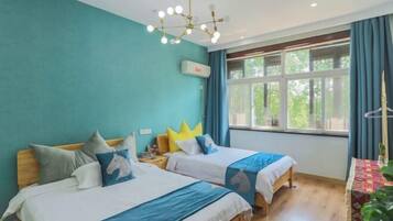 Una habitación con dos camas, una lámpara en el techo, una ventana con cortinas y una mesa con una planta.