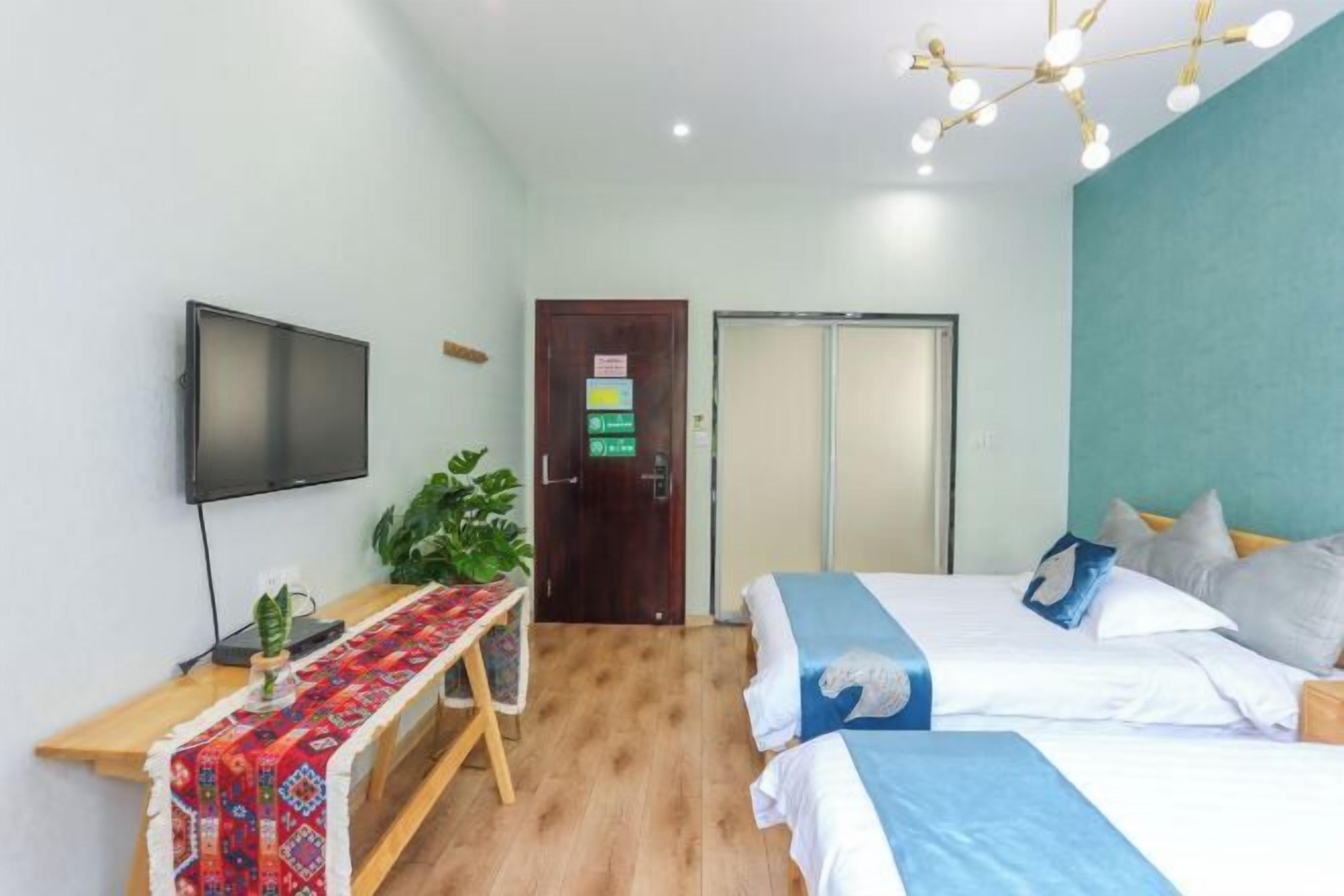 Habitación de hotel con cama, mesita de noche, televisor y una puerta con un letrero.
