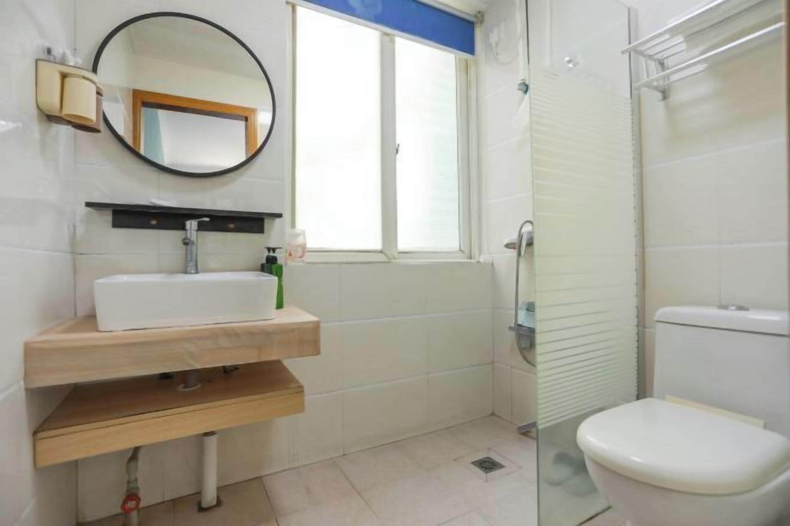A bathroom with a white sink, mirror, and toilet.