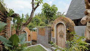 A courtyard with a brick wall, a wooden door, and a stone archway. - Agastya Ubud Villa (Ubud)