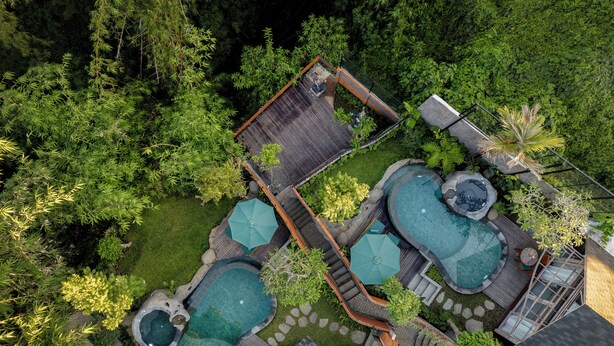 An aerial view of a residential property with multiple swimming pools, a wooden deck, and lush greenery. - Agastya Ubud Villa (Ubud)