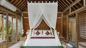 A room with a four-poster bed, wooden flooring, a green bench, a small table, and a nightstand with a lamp. - Agastya Ubud Villa (Ubud)