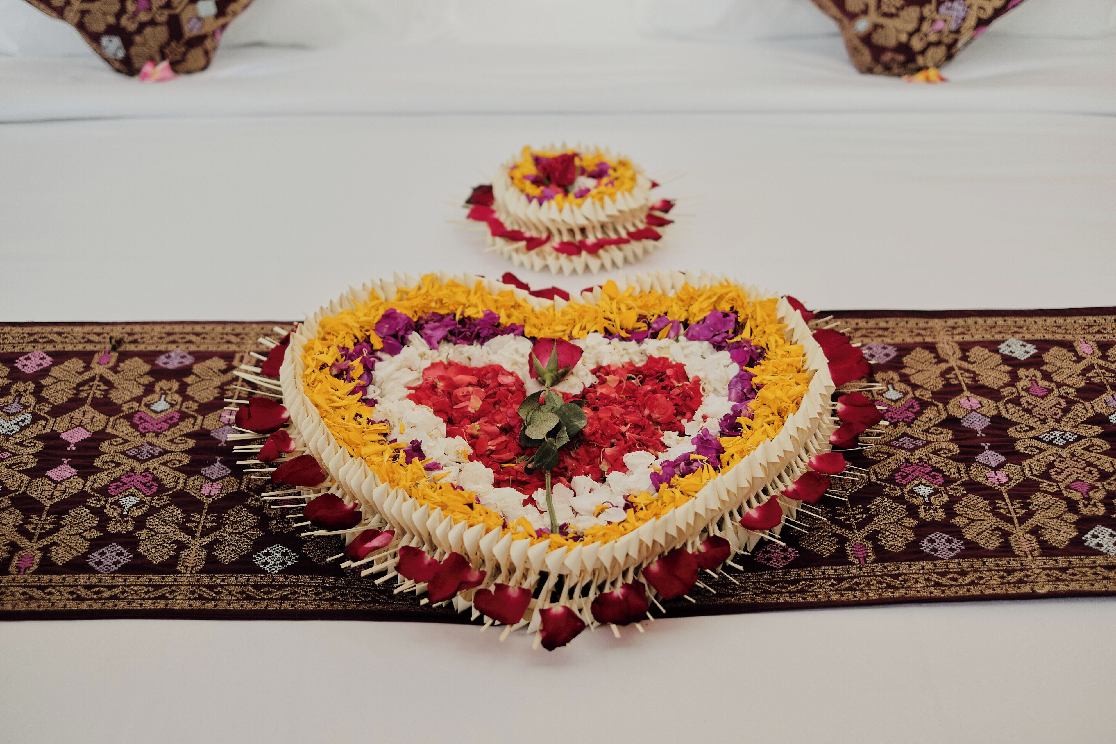 Un'elegante composizione a forma di cuore con fiori e un tessuto decorato.