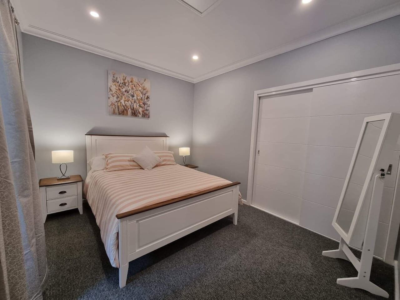 A bedroom with a bed, nightstands, a wall-mounted artwork, and a wardrobe.