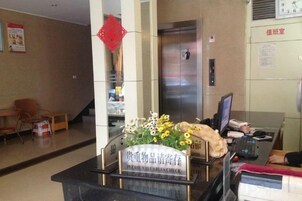 Una mesa de recepción con un cartel, una computadora y una silla.