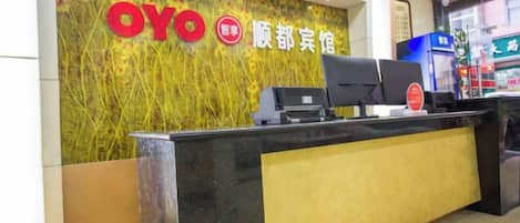 A reception desk with a black and yellow color scheme, a digital screen, and a wall with the OYO logo and Chinese characters.