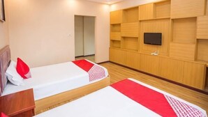 Ein Hotelzimmer mit zwei Betten, einem Wandfernseher und einer Holzausstattung.