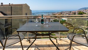 Un balcon avec une table et des chaises donnant sur un paysage urbain le long de la côte.
