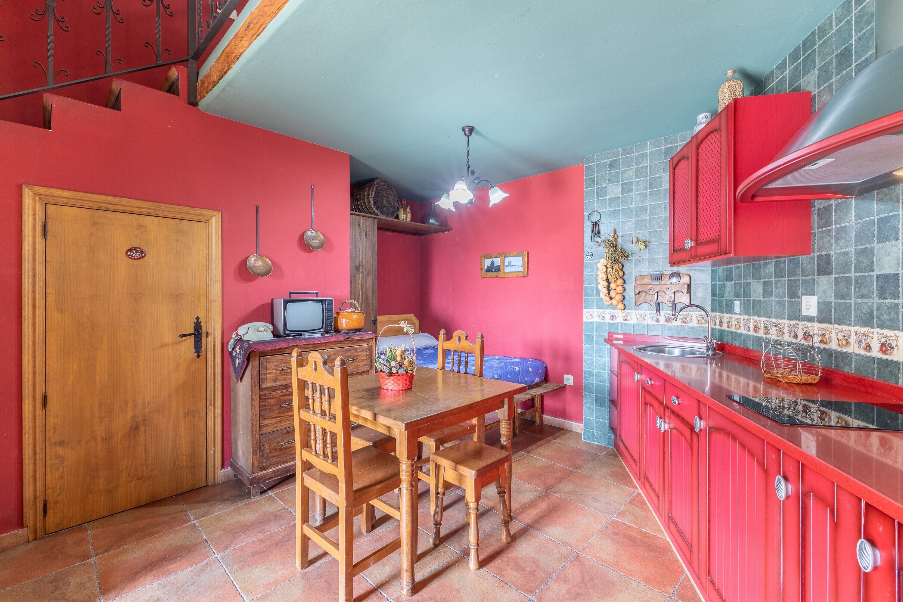 A compact kitchen with a dining area, wooden furniture, and a red cabinet.