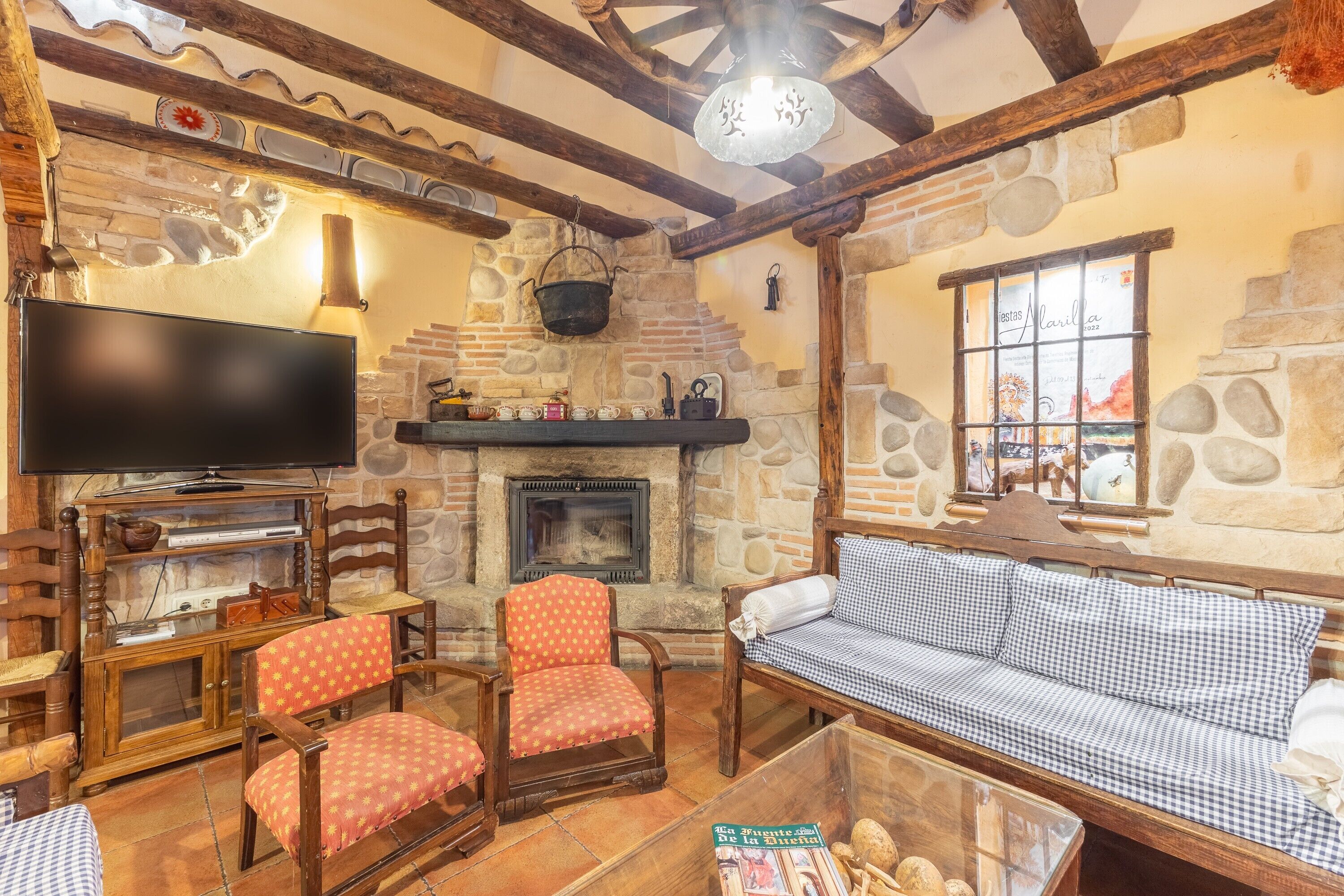 A cozy living room with a stone fireplace, wooden furniture, and a television.