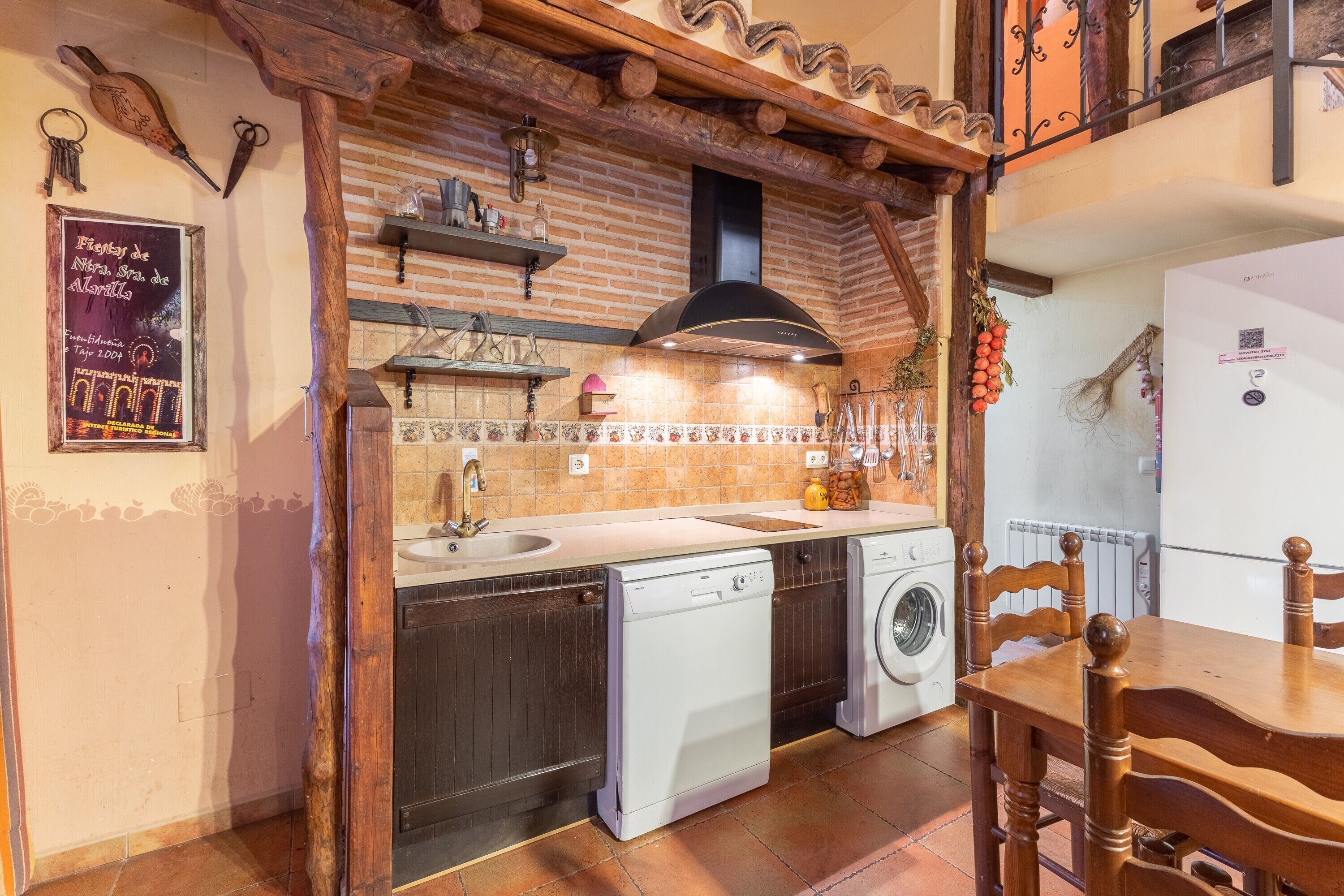 Una cocina con lavavajillas, lavadora y mesa de madera.