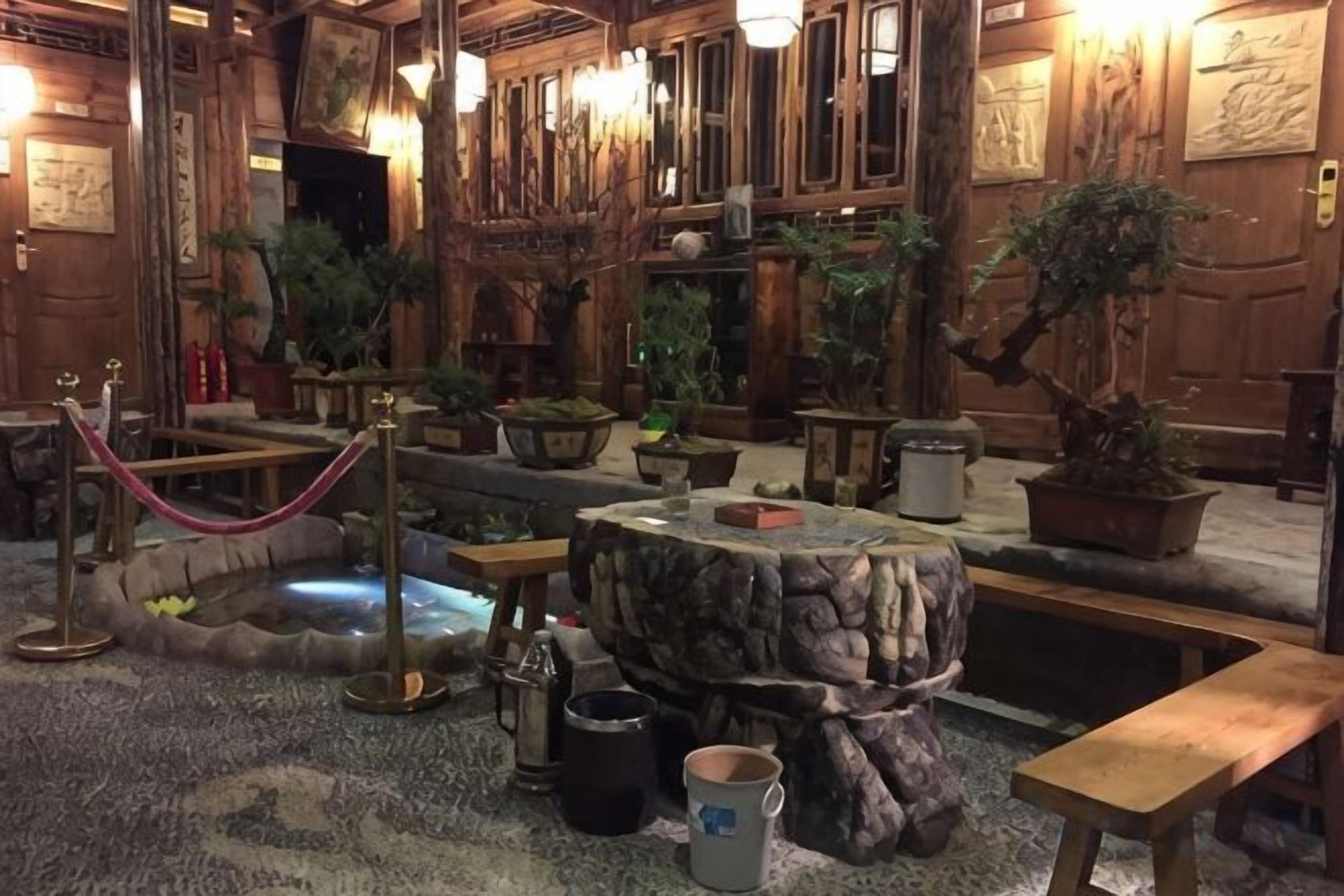 A traditional Japanese-style interior with tatami flooring, a koi pond, and potted plants.