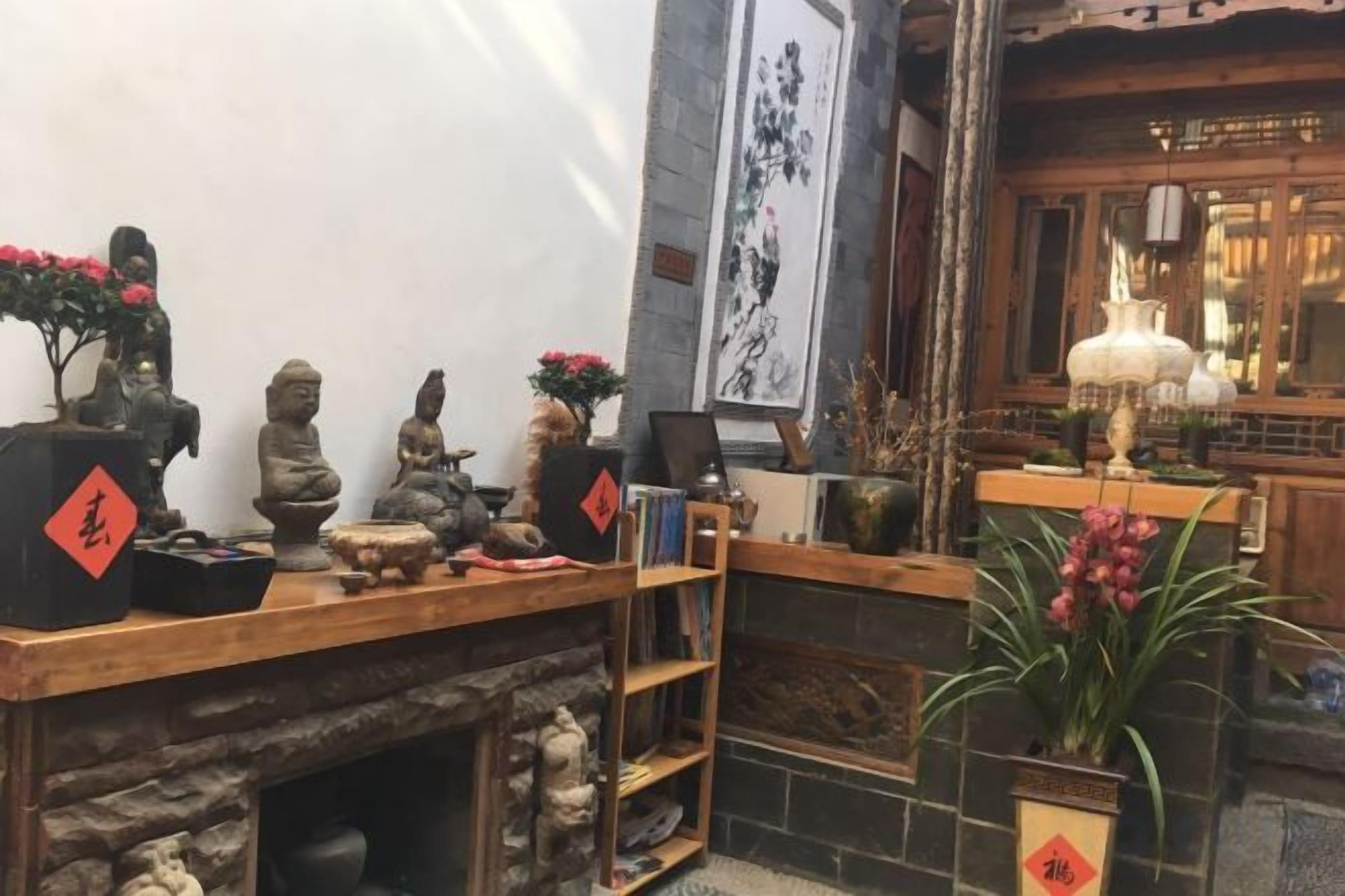 A traditional room with a wooden shelf displaying statues and a stone fireplace.