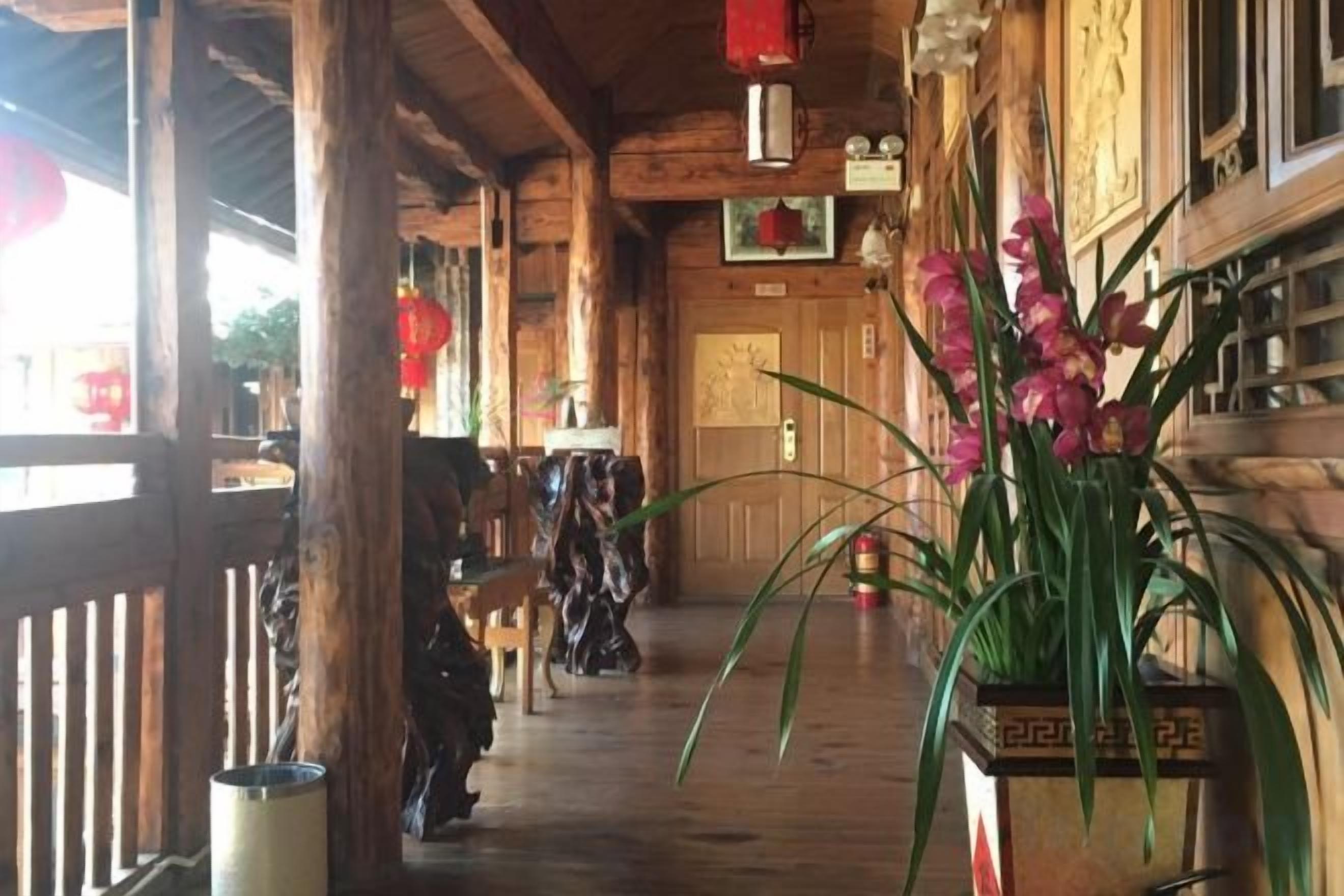 A wooden corridor with a wooden railing, a potted plant, and a door at the end.