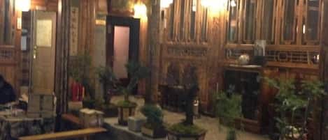 A traditional interior with wooden paneling, multiple seating areas, and potted plants.