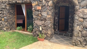 Un edificio de piedra con un letrero que dice 'La Cuina', puerta de entrada de vidrio y un pequeño jardín con plantas en macetas.