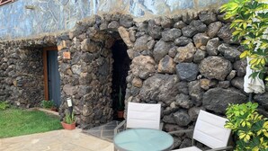 Un muro de piedra, una puerta y un patio con sillas y una mesa.