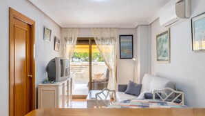 A room with a bed, a TV on a small table, a door, and a view of the outside. - Apartment 'Calp Place Wifi Fibra' with Sea View, Wi-Fi and Air Conditioning (Calpe)