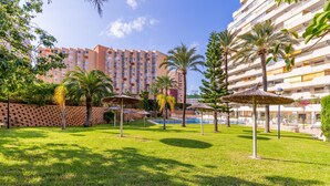 A hotel courtyard with a swimming pool, palm trees, and a brick wall. - Apartment 'Calp Place Wifi Fibra' with Sea View, Wi-Fi and Air Conditioning (Calpe)