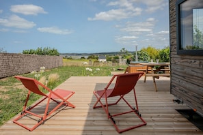 En træterrasse med to røde stole, et træbord og udsigt over landskabet.