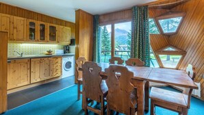 A kitchen with wooden cabinets, a washing machine, and a dining area with a table and chairs.