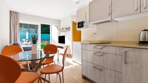 Una cocina moderna con una mesa de comedor de vidrio, sillas color naranja y vistas al exterior.