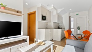 Una sala de estar moderna con un televisor de pantalla plana, una mesa de centro de madera y un sofá gris.